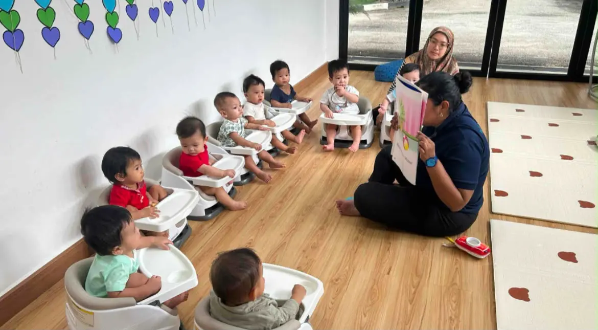 Babies seated in a circle while a teacher reads to them