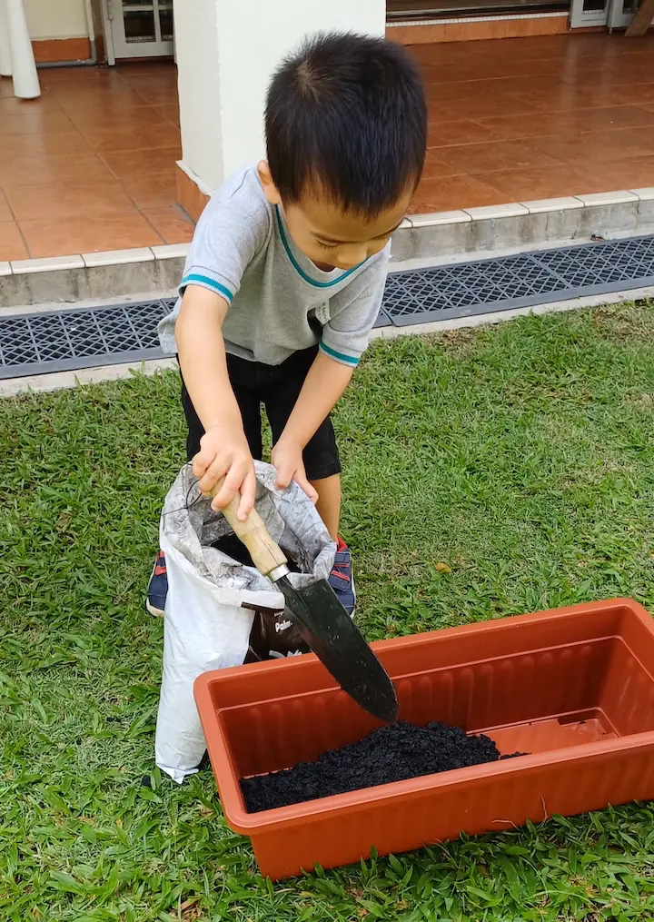 A child tidying up on the grass outdoors
