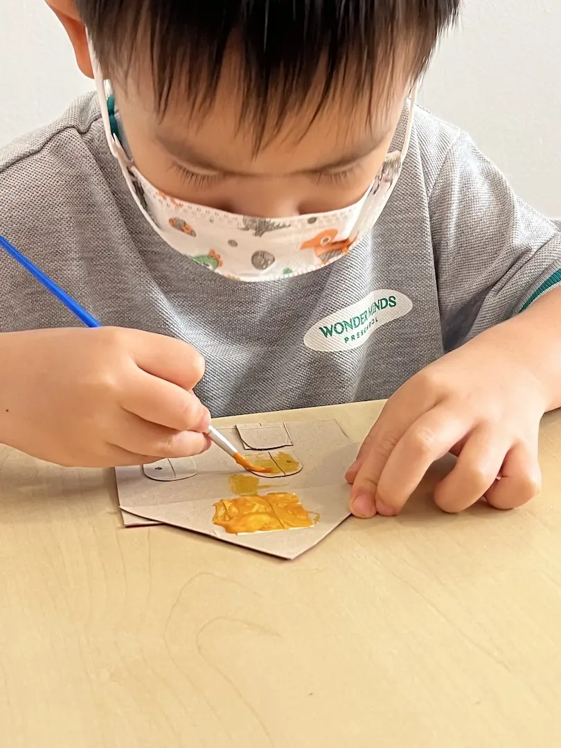 A child painting cardboard shapes