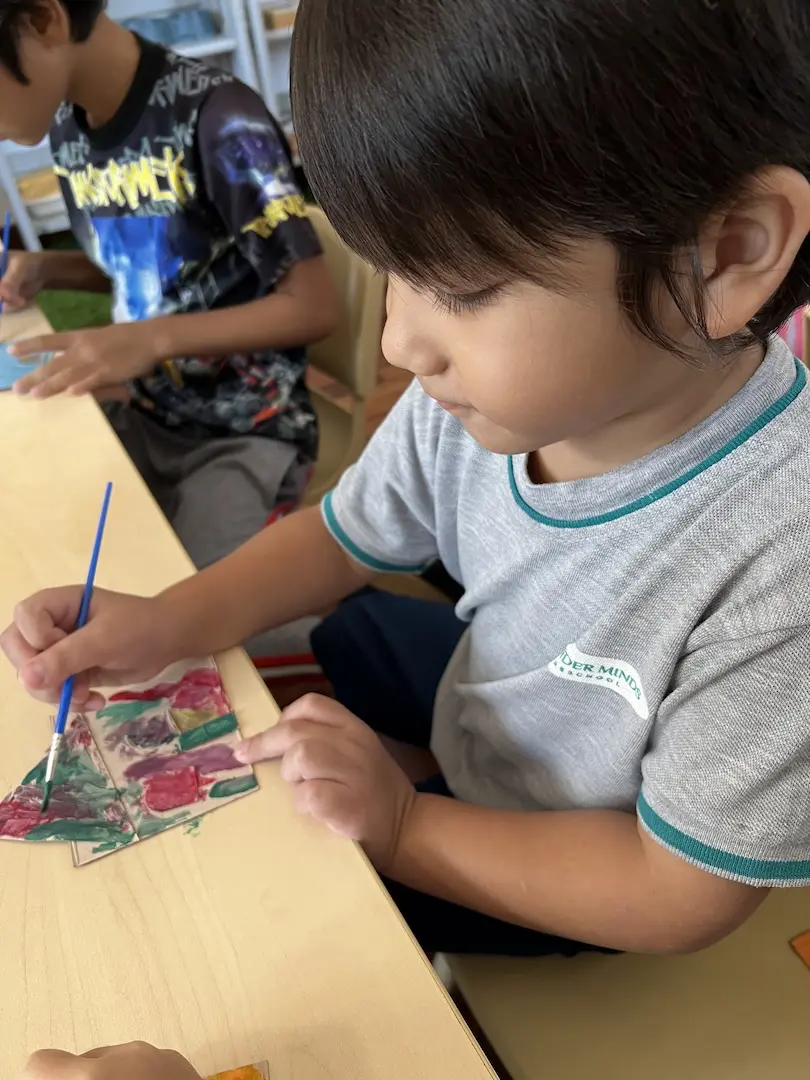 A boy painting a colourful collage