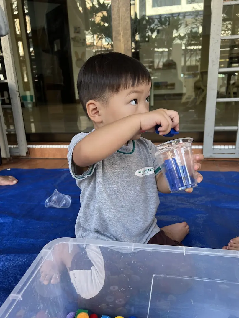 A boy holding a cup of blue water