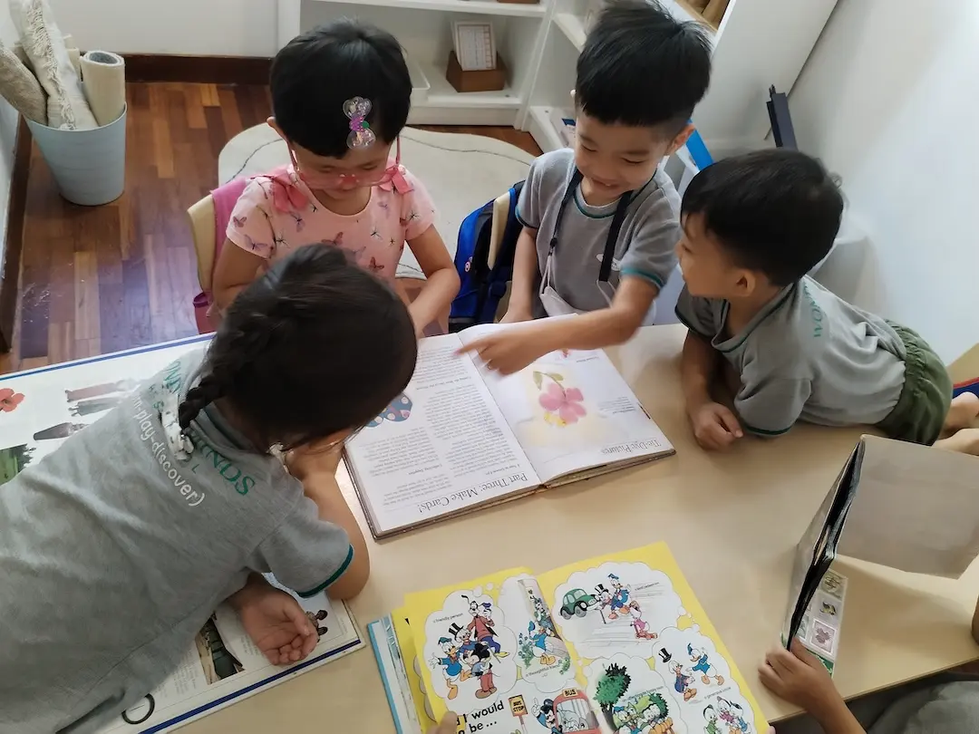 Children reading a picture book together at a table