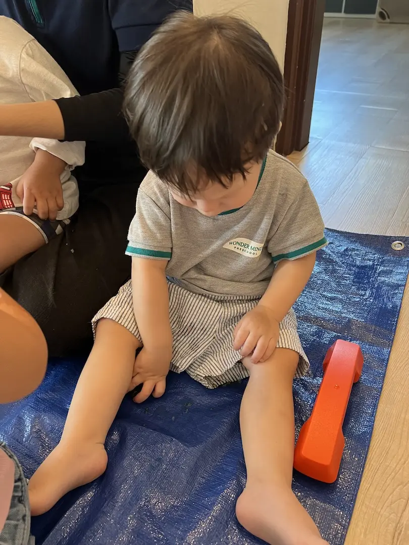 A toddler sitting on a blue mat during floor play