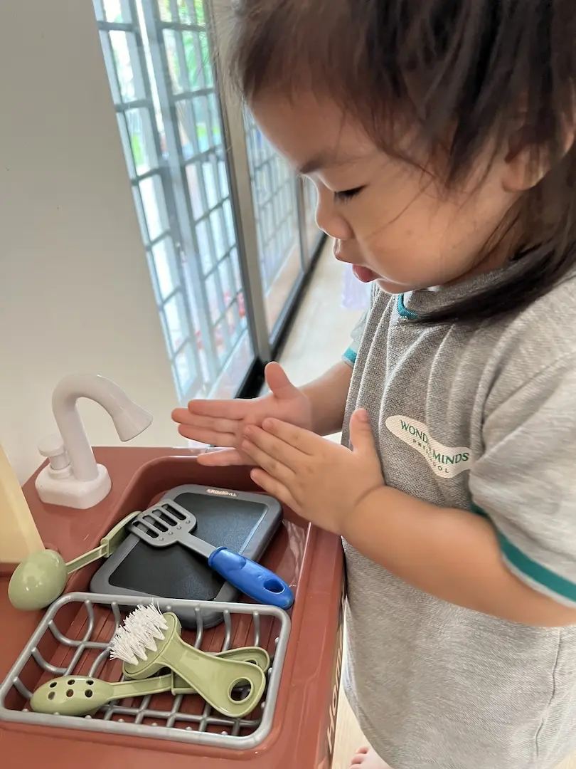 A girl washing her hands at a play sink