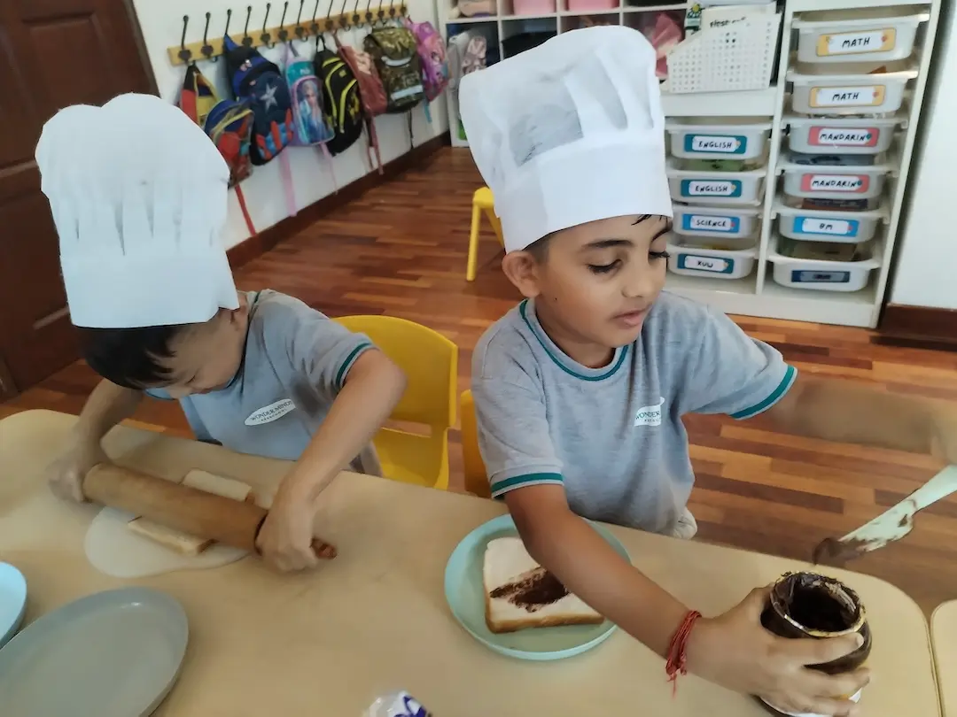 Two boys in chef hats rolling dough
