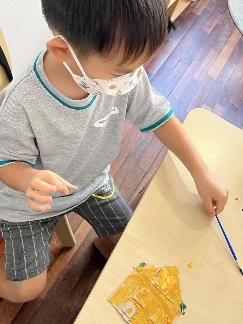 A boy painting with a thin brush at a table