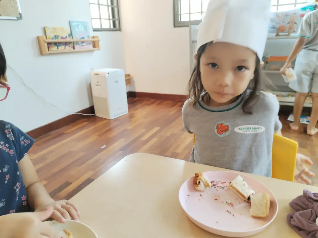 A girl in a chef hat with her finished snack