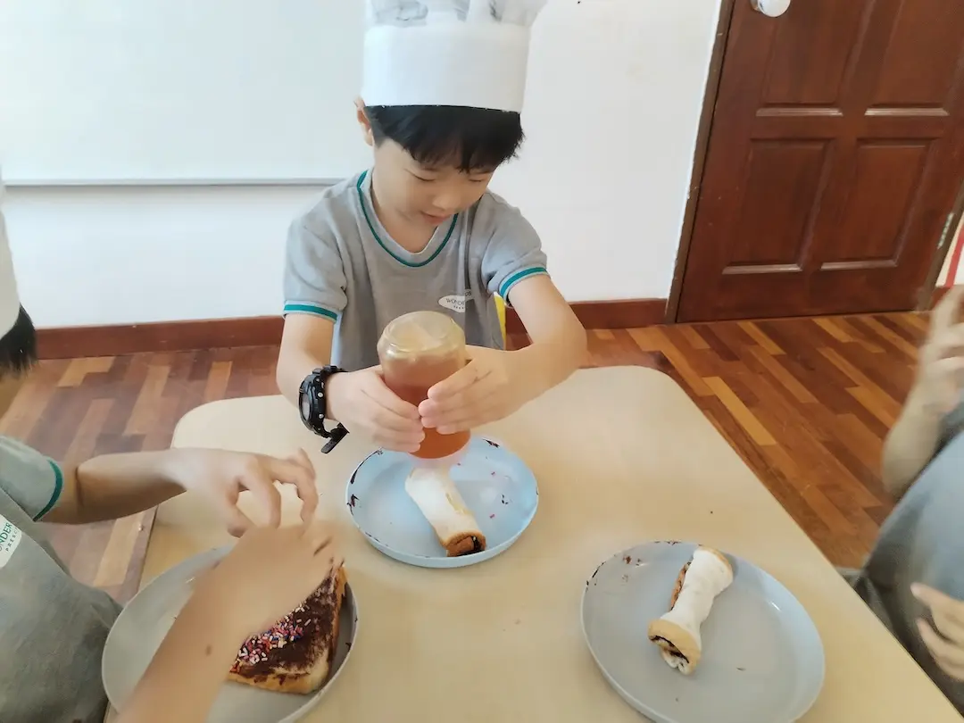 A boy in a chef hat making a snack