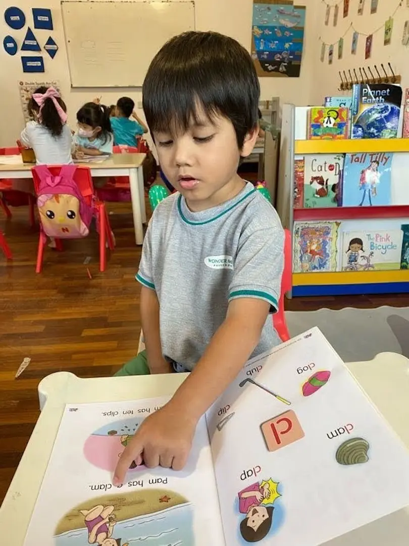 A boy at a table with a phonics card