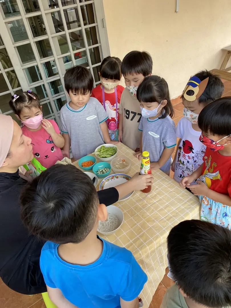 Children and a teacher gathered around a table of ingredients