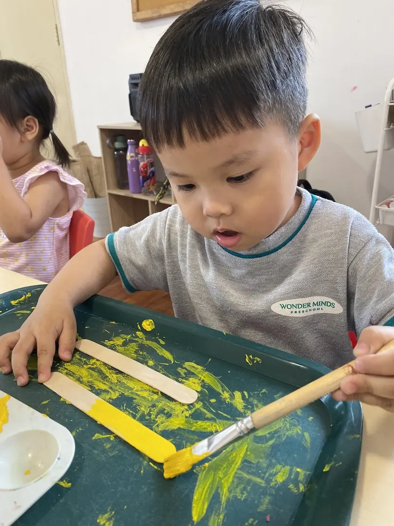 A boy painting yellow stripes in a paint tray