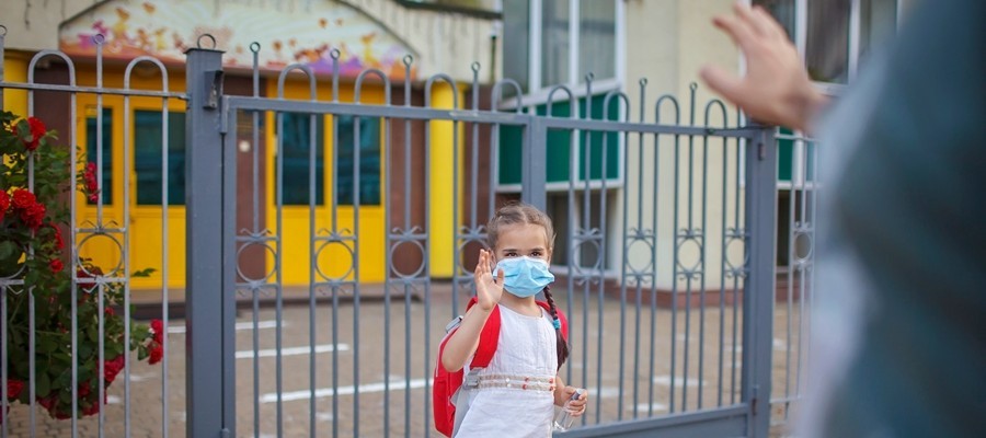 girl wearing a mask and waving