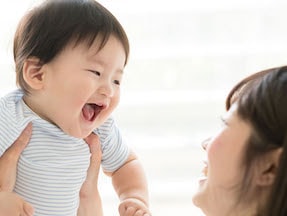 laughing toddler carried by mother