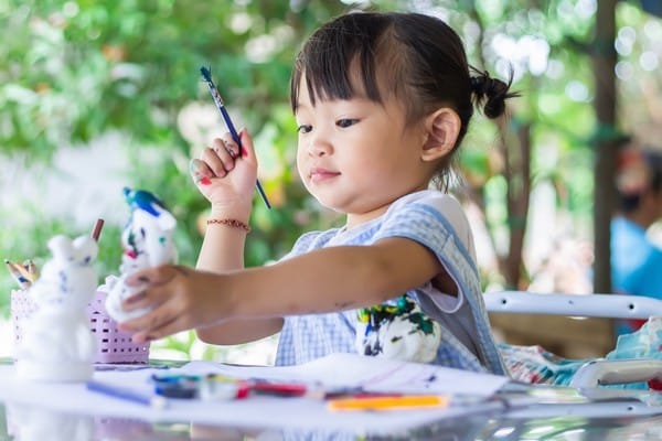 little girl painting figures with brush