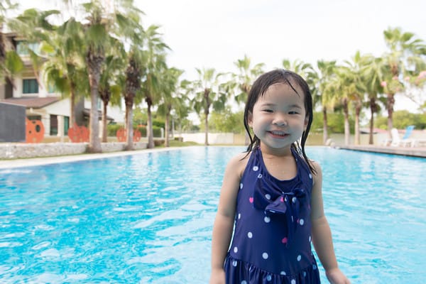 girl smiling in front of a swimming pool
