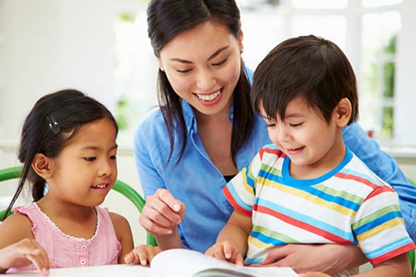 kindergarten teacher reading with two students