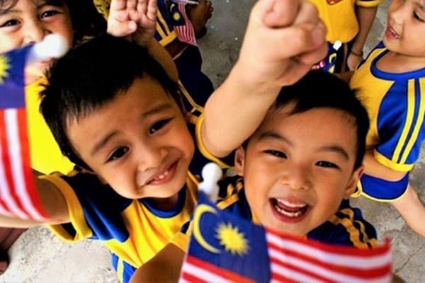 malaysian kids smiling while waving flag
