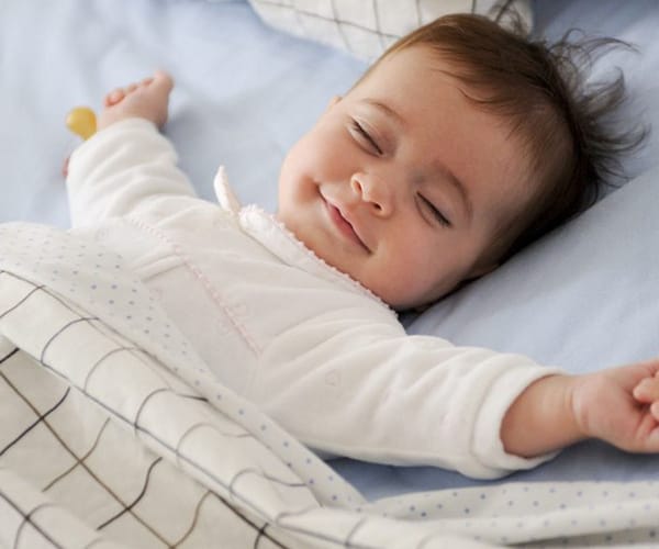 infant smiling in bed