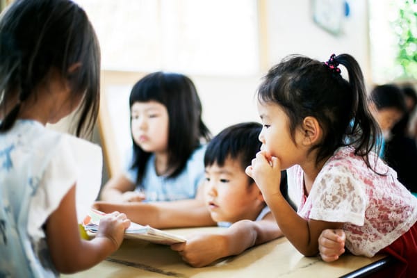 a group of asian kids in a preschool classroom reading